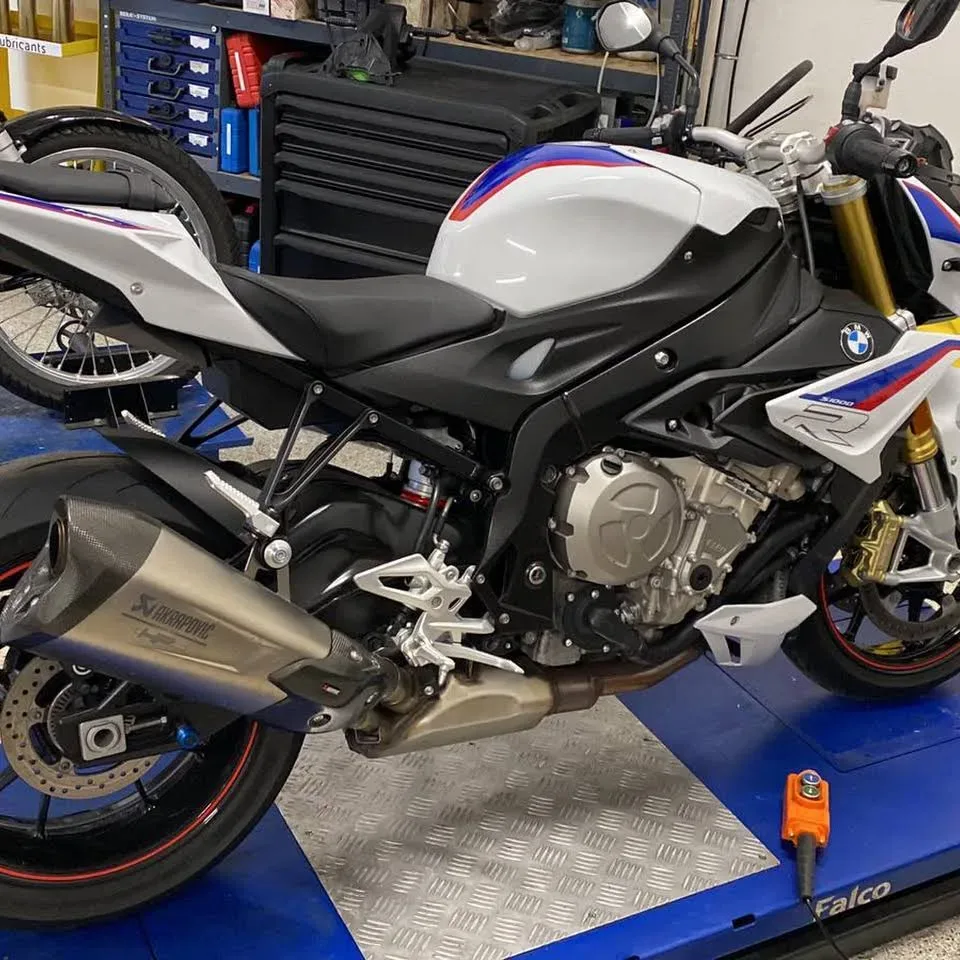 Kleiner blauer Suzuki-Motorroller im Innenraum neben einem Heizkörper.
